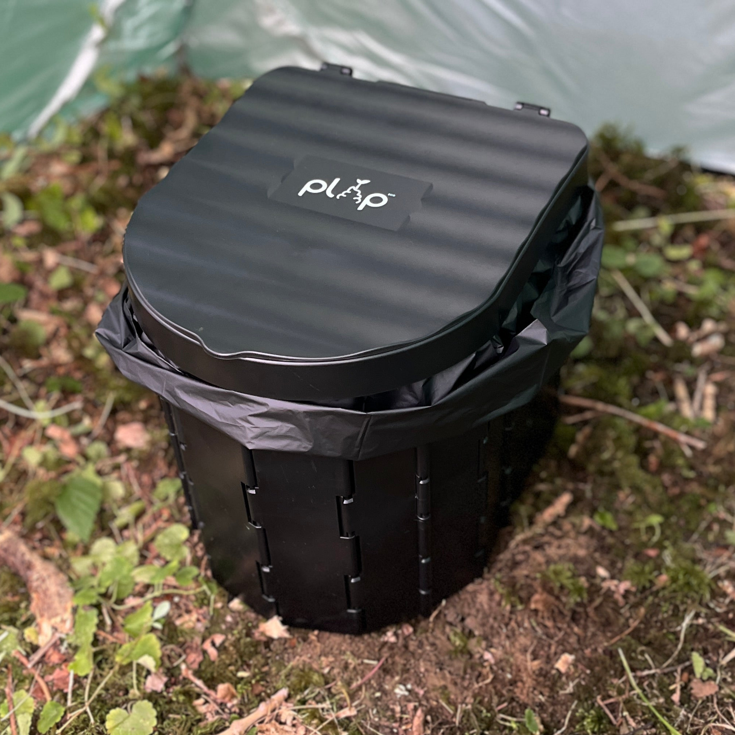 Black PlopEco GO Toilet Kit with lid on a natural background