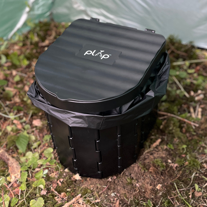 Black PlopEco GO Toilet Kit with lid on a natural background